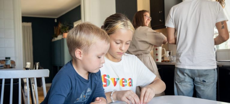 Barn som sitter i köket och föräldrar står vid bänken