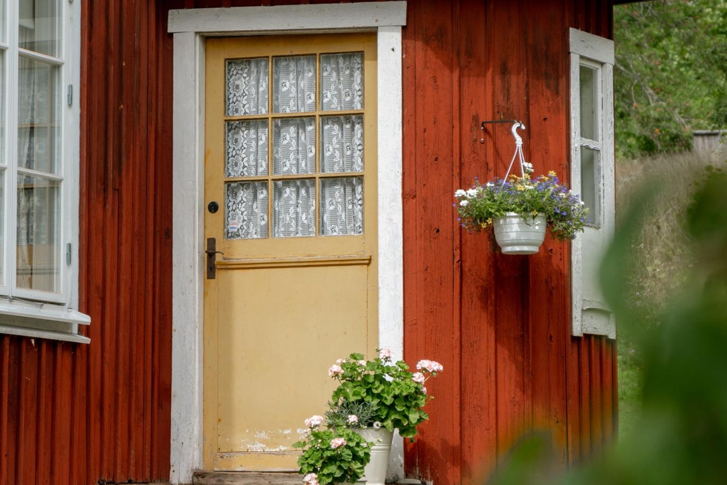 Rött hus med dörr och blommor på trappan