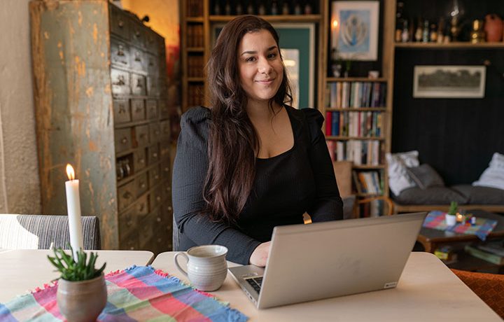 Erika Stadling Holm sitter vid kökbordet med en dator