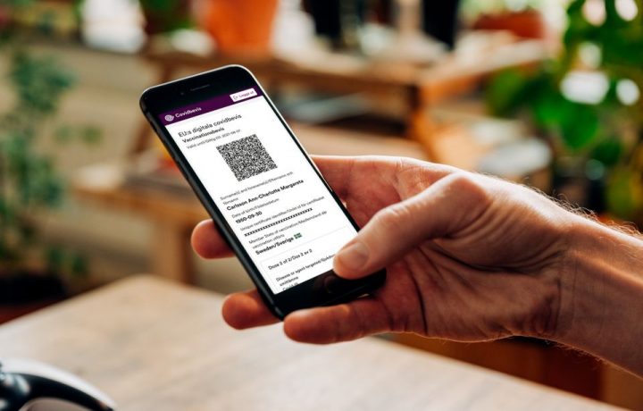 En hand håller en mobiltelefon som visar ett covidbevis