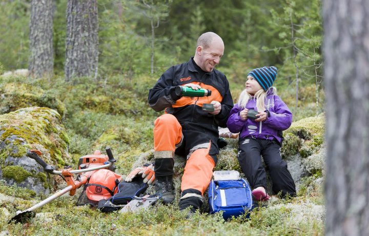 Man och flicka sitter i skogen och fikar