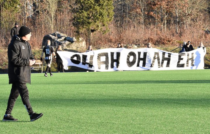 En fotbollstränare promenerar på en fotbollsplan.