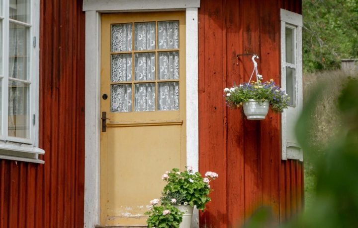 Rött hus med dörr och blommor på trappan