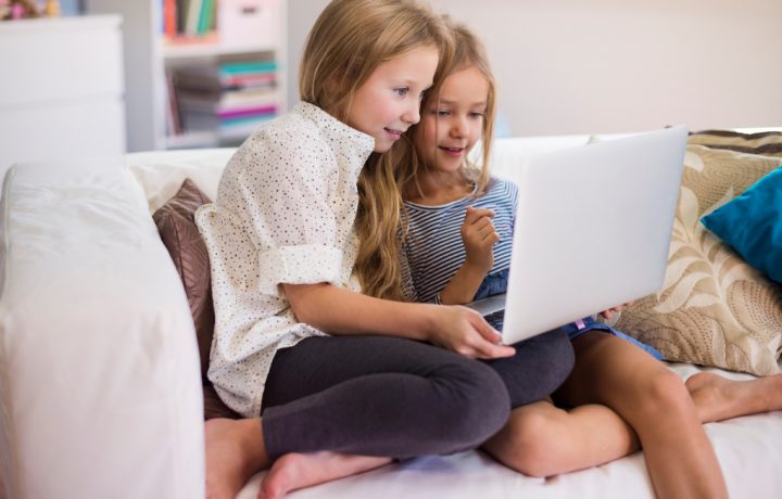 Två flickor sitter framför en laptop