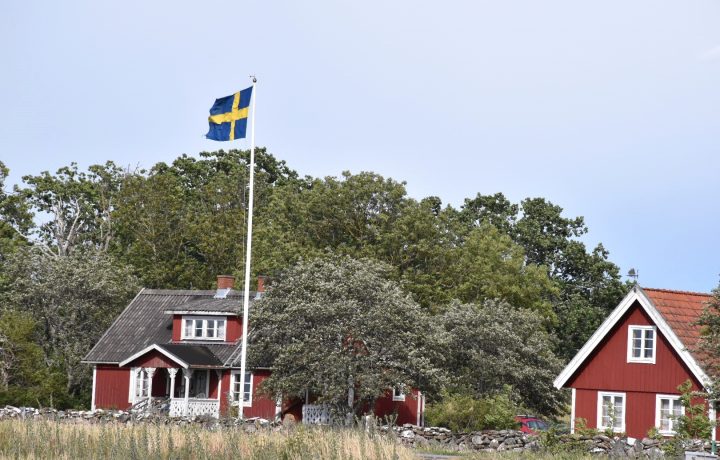 Genrebild Sverige, rött hus med vita knutar, svenska flaggan, hus, sommar