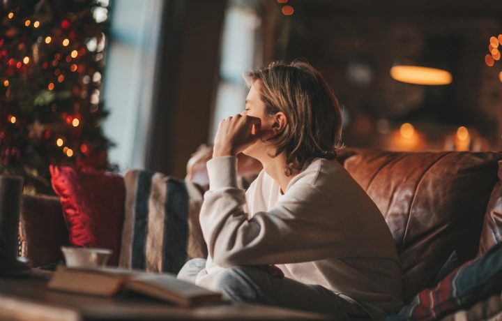 Pojke sitter i soffan vid julgranen och ser deppig ut