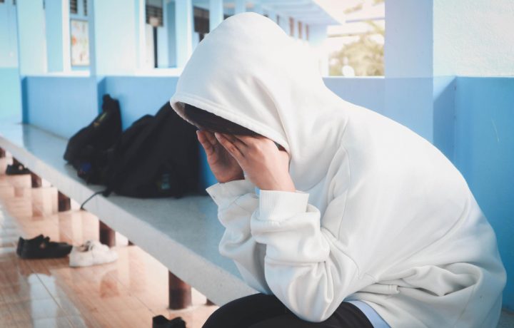 Ledset barn sittandes på bänk i skolan