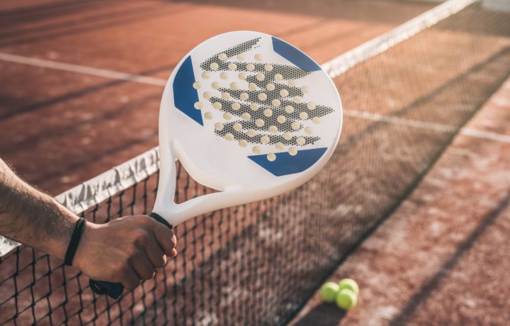 Manlig hand som håller i ett padelracket