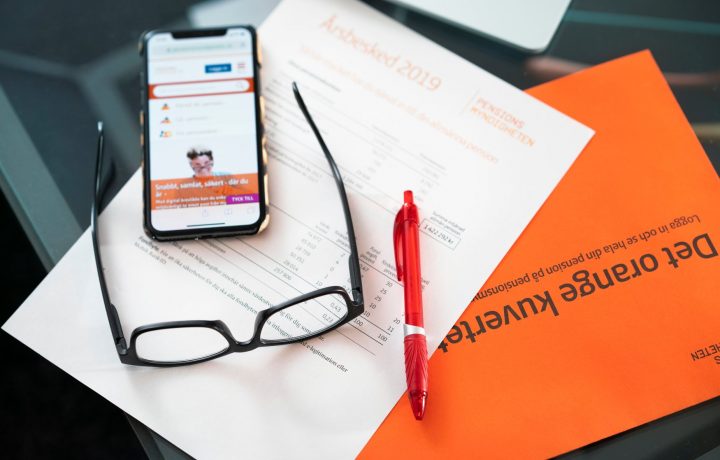 Orange kuvert med årsbesked, mobil och glasögon