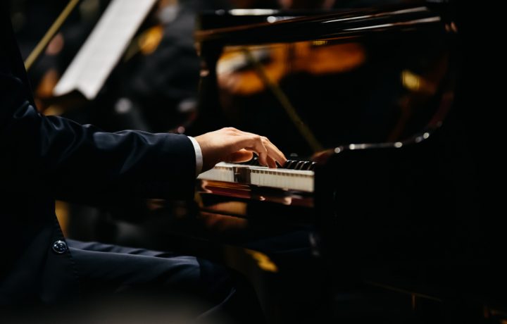 Pianist som spelar på ett piano sett från sidan