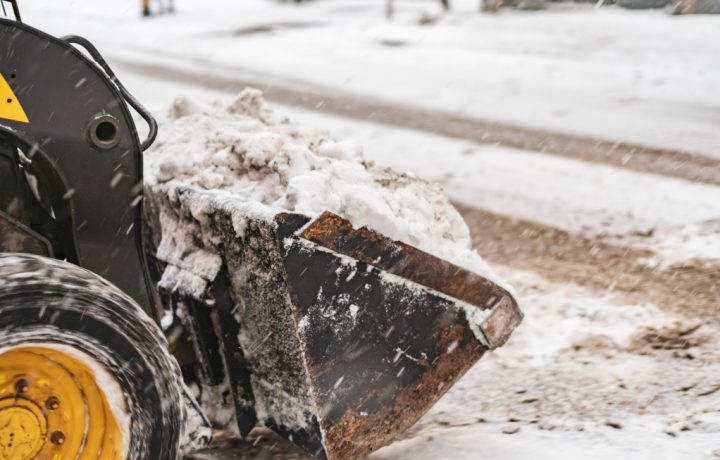 Trakror med skopa full av snö